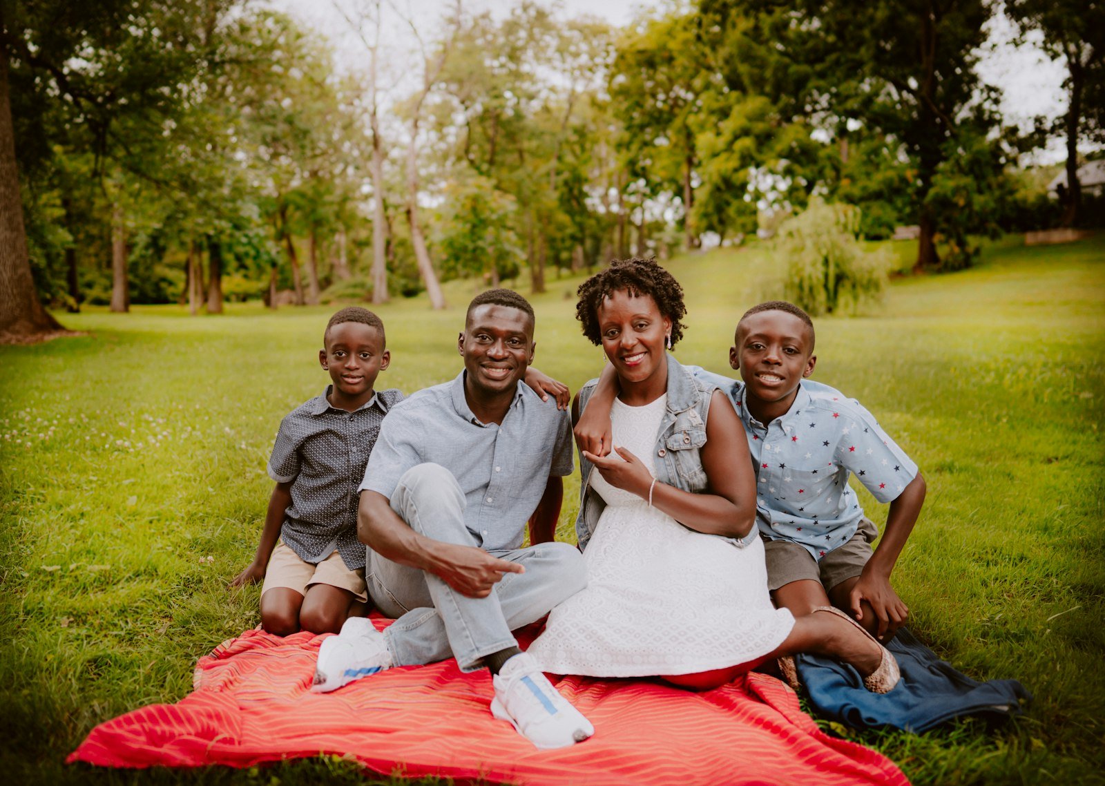 Multigenerational family of five sitting outside on a green field on a sunny day