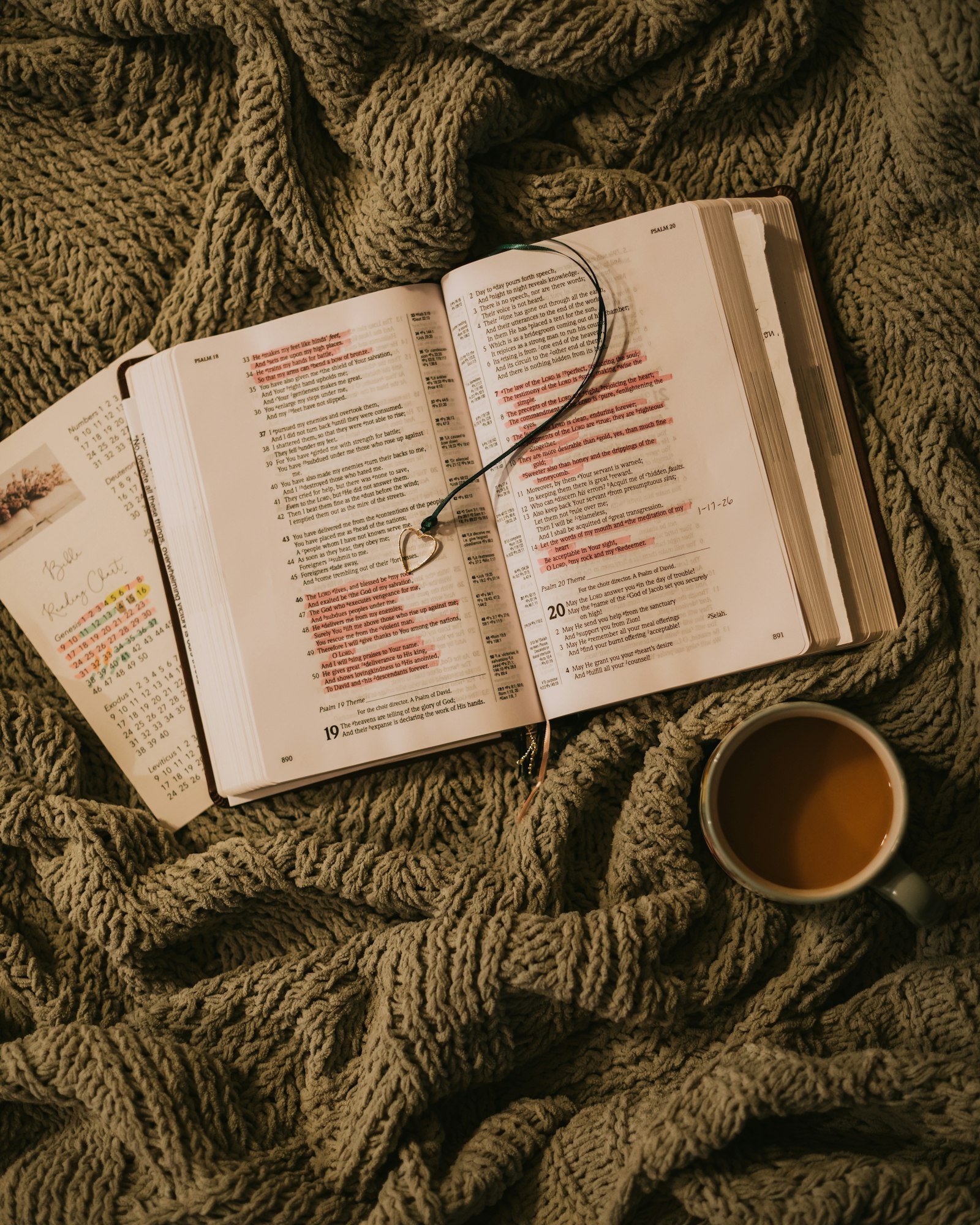 Open book with coffee cup and a calendar on a textured blanket, used for daily devotion