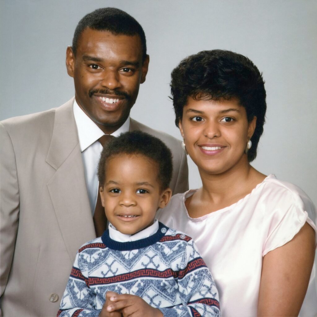 A young Black family of three in soft natural light, parents holding their child