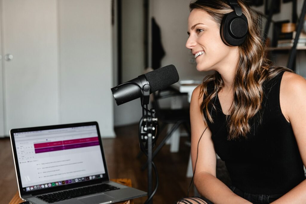 Woman in a black tank top seated at a desk in front of a studio microphone