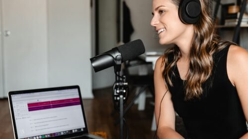Woman in a black tank top seated at a desk in front of a studio microphone