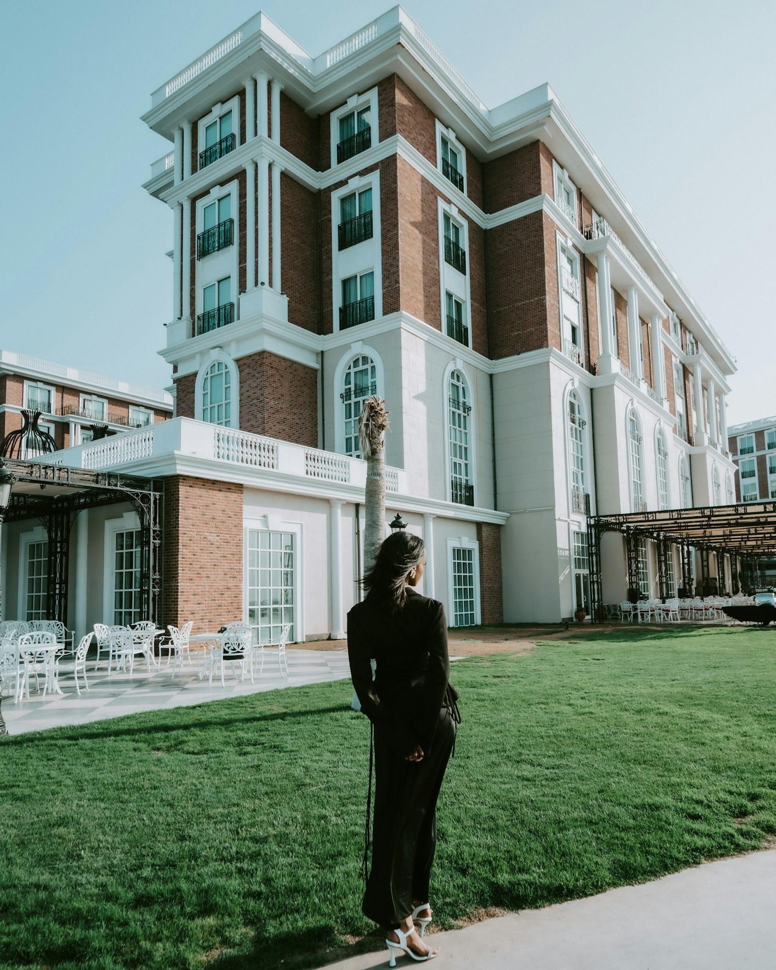 Black woman in a confident posture standing in front of a modern brick building