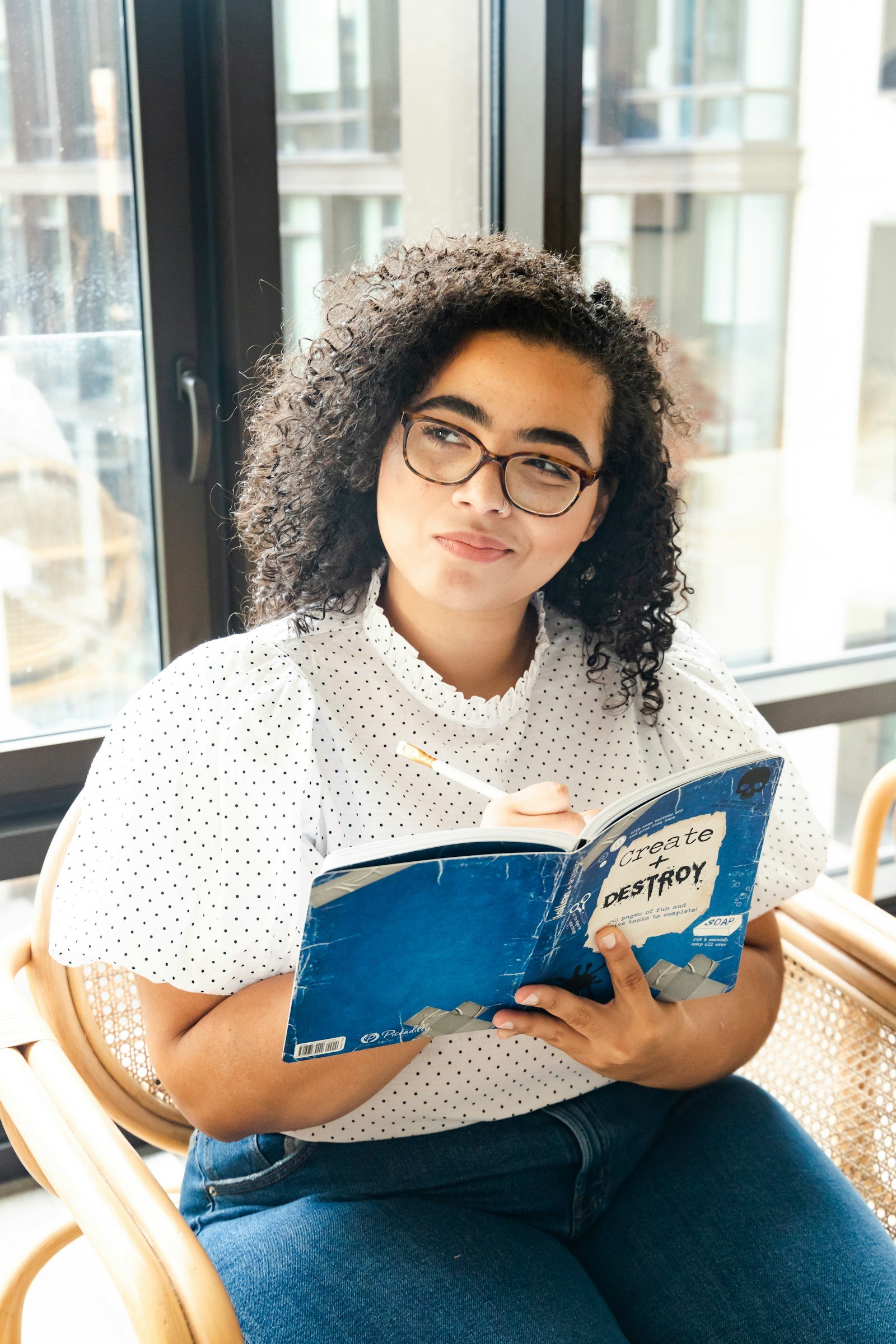 Woman in a polka dot shirt holding an open book, looking down at the pages