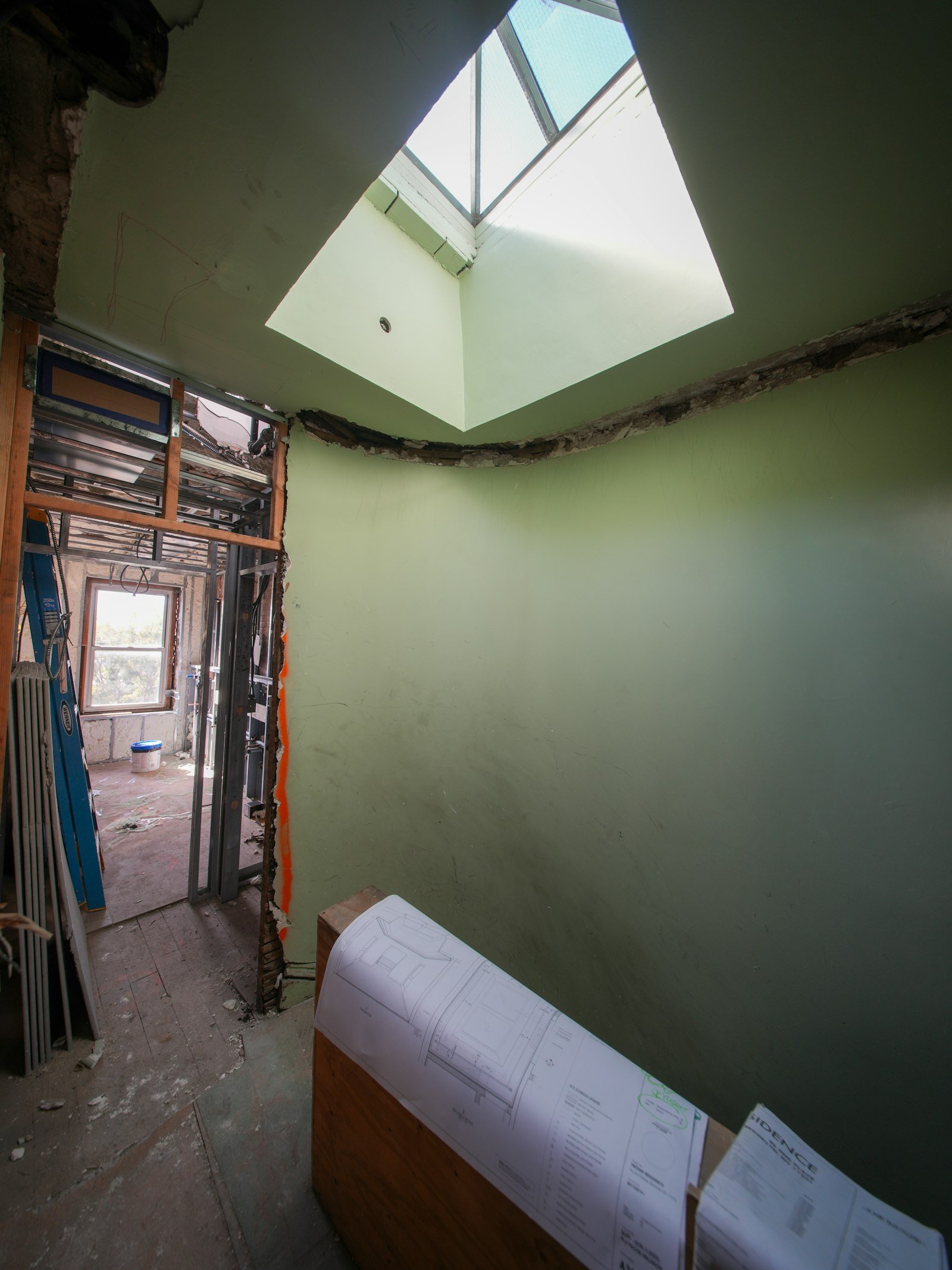 Interior of a residential build under construction with skylight overhead and blueprints scattered on the floor